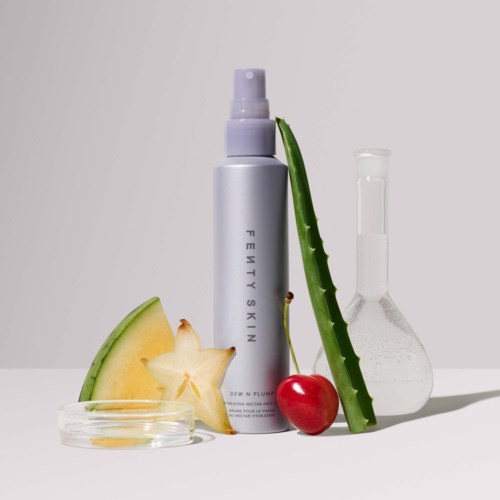 A skincare spray bottle with aloe vera, cherry, starfruit, and a beaker with clear liquid.