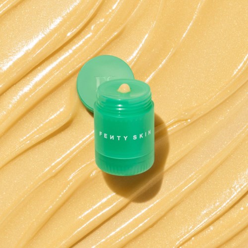 Vihreä Fenty Skin -rasia kiinnikkeessä kiiltävällä kullanruskealla pinnalla, kannen kanssa.