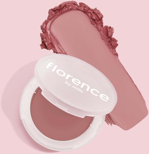 A blush compact with a swatch of pinkish-brown makeup behind it on a light pink background.