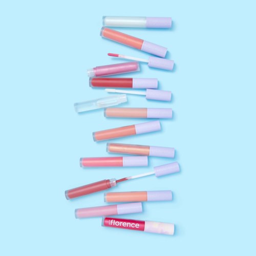 Multiple lip gloss tubes in various shades arranged on a light blue background, with one labeled "Florence."