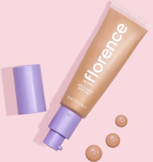 A beige tube of Florence skin tint with purple cap and three dollops on pink background.