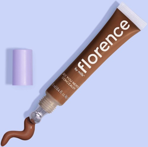 En tub med Florence-concealer med lila lock på en ljusblå bakgrund. Tuben är öppen, med lite produkt som pressats ut.