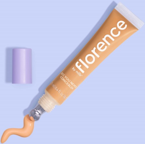 En beige concealer-tuber med vitt text, lila lock och en liten mängd produkt som kommer ut.