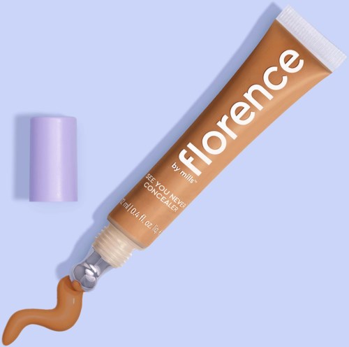 En concealer-kräm i tub med lila lock och beige färgad kräm på en blå yta.