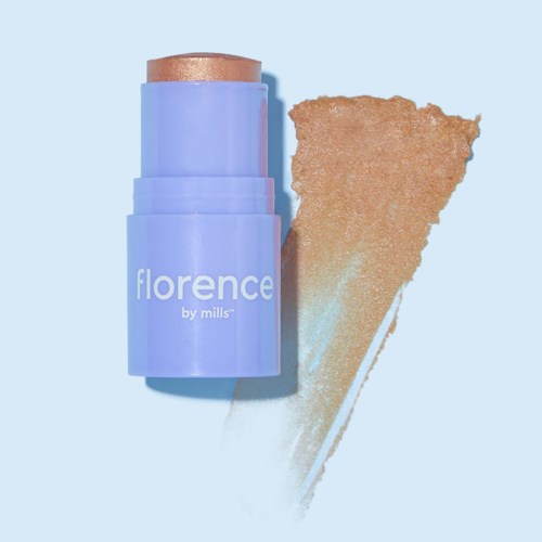 En lila makeup-stift märkt 'florence by mills' med guldspets, bredvid ett prov av produkten på en blå bakgrund.