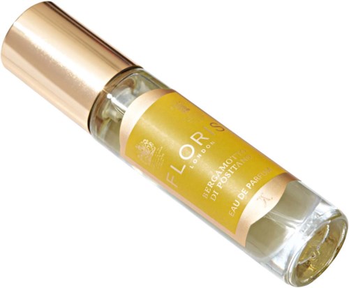 Mała butelka perfum z złotą nakrętką i żółtą etykietą, leżąca skośnie. Zawiera Eau de Parfum. Elegancki i prosty design.