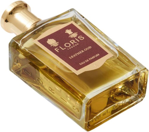 En gullfarget parfymeflaske ligger på siden med en brunsvart etikett som sier 'Floris London Leather Oud Eau de Parfum'.