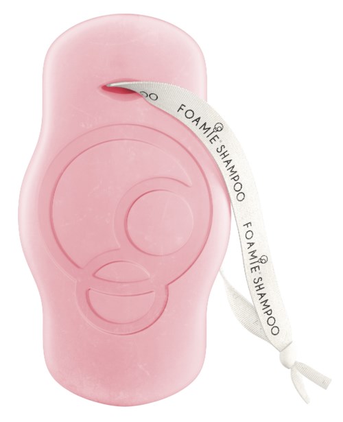 A pink soap dispenser designed for shampoo, with a white ribbon labeled "Foamie Shampoo" hanging from the opening.
