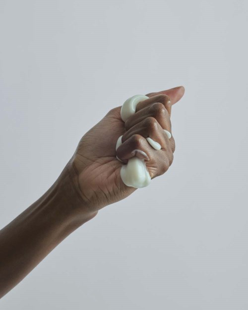 Två händer som pressar ut kräm eller lotion med en enkel ljus bakgrund.