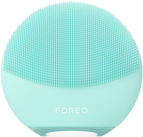 A round, mint-colored device with many small bumps on the top surface and the word 'FOREO' on it.