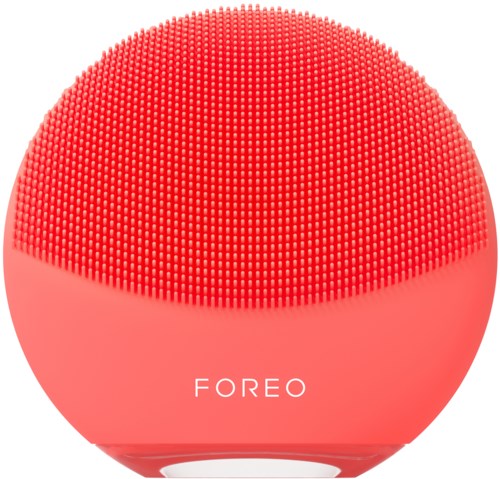 A pink, round facial cleansing device with tiny silicone bristles and the brand name 'FOREO' on it.