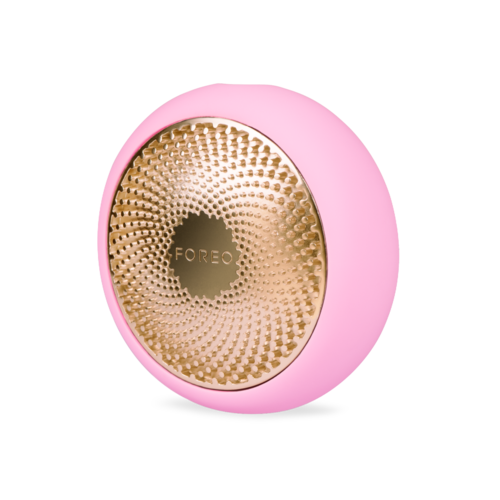 Dette er en rosa, rund enhet med en gylden, teksturert senter merket "FOREO."