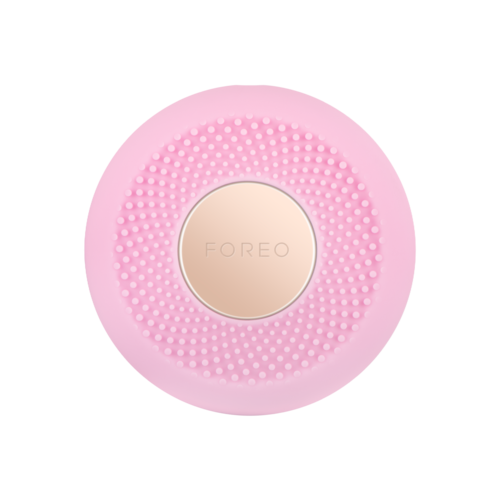 Rosa cirkulär skönhetsenhet med små knölar runt en beige mittdel märkt 'FOREO'.