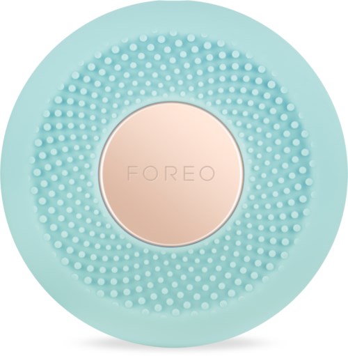 En rund, mintgrön enhet med små vita prickar runt den centrala, beige delen med varumärket 'FOREO'.