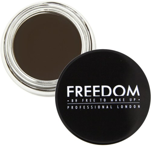 En svart rund beholder med orden "FREEDOM" og "BE FREE TO MAKE UP" skrevet på toppen, og lokket er åpent og viser brunt innhold.
