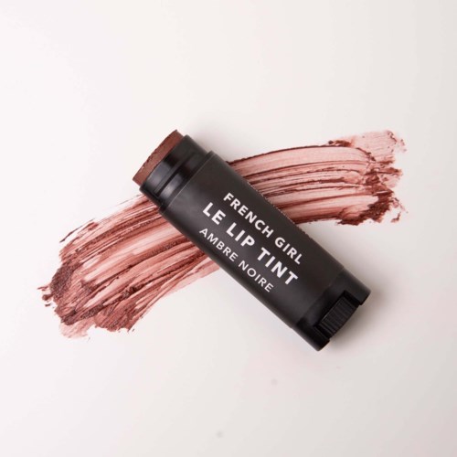 A black lip tint stick labeled "French Girl" with a brownish pink shade swiped on white background.