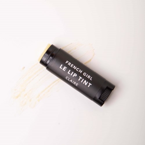 A black lipstick tube with white text that reads "FRENCH GIRL LE LIP TINT CLAIRE." Looks used with smudges nearby.