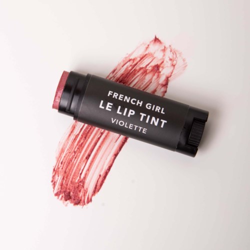 A black lip tint tube with white text, swiped across a white surface with a red lip stain.