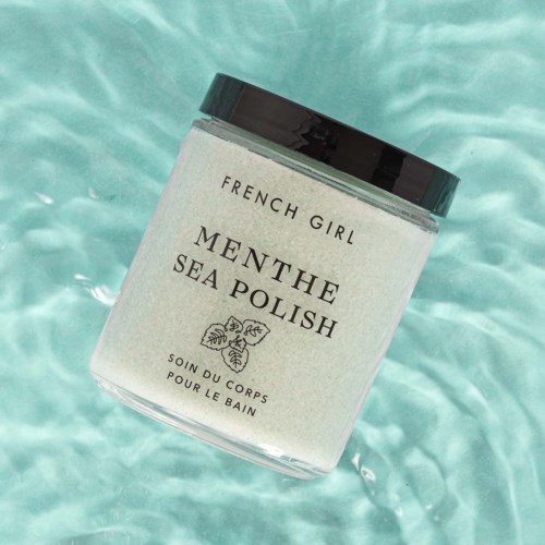 A jar labeled 'French Girl Menthe Sea Polish' floating in water. It is a body scrub for bathing.