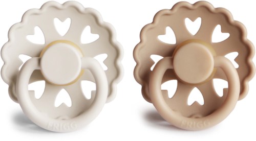 Zwei Schnuller in Blumenform mit Herzlöchern, einer weiß und einer beige, jeweils mit einem Ringgriff.