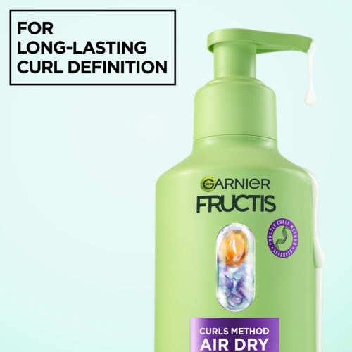 Grön Garnier Fructis schampoflaska med pump, märkt för långvarig lockdefinition.