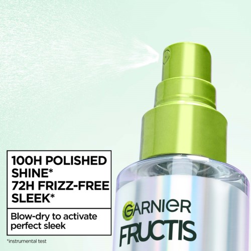 En sprayflaske mærket Garnier Fructis med tekst om shine og frizz kontrol. Den spreder en fin tåge.