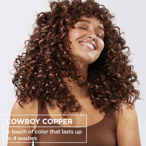 Hübsche Frau mit Locken und einem Lächeln, wirbt für Cowboy Copper Haarfarbe, die bis zu 4 Wäschen hält.