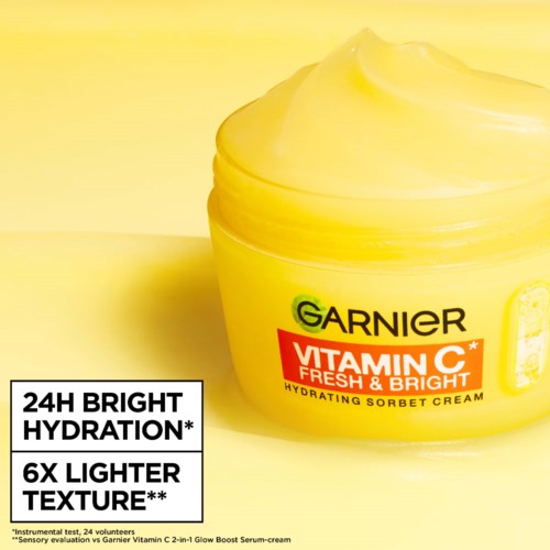 Ein gelbe Dose mit Deckel enthält Garnier Vitamin C Feuchtigkeitscreme, hervorhebend helleres Hautbild und Feuchtigkeitsversorgung.