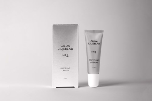 Paczka na usta obok tubki na zwykłym tle, obie oznaczone Gilda Liljeblad No. 4, Fortifying Lip Balm.