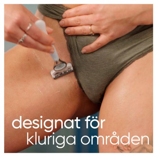 Joku ajaa toisen henkilön bikinialuetta partahöylällä mustissa vaatteissa.