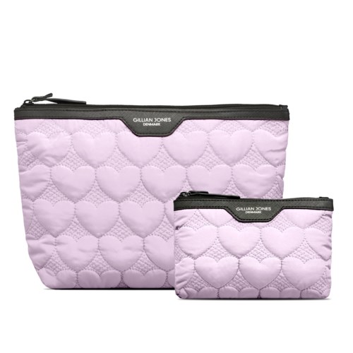 Två quiltade väskor med hjärtmönster, en stor och en liten, rosa färg, med svarta blixtlås och märkningar.
