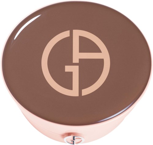 Ett runt föremål med brunt lock och en logo i mitten, möjligen en kosmetik- eller makeup-produkt.