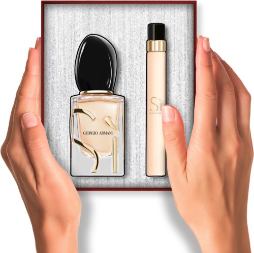 Giorgio Armani parfum en een beige stick in een doos, vastgehouden door twee handen.