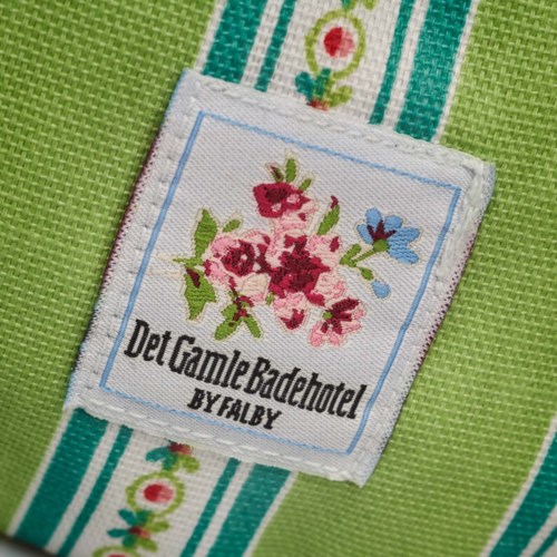  Kaulanauha kukkakuvioilla ja tekstillä 'Det Gamlé Badehotel by Falby' värikkäällä kankaalla.