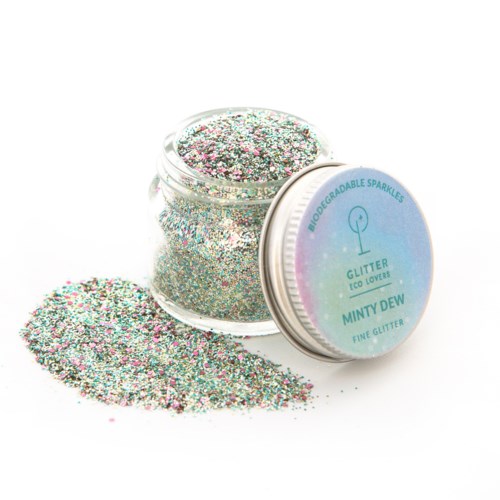 En burk med färgglitt glitter och lite spilld på en vit yta.