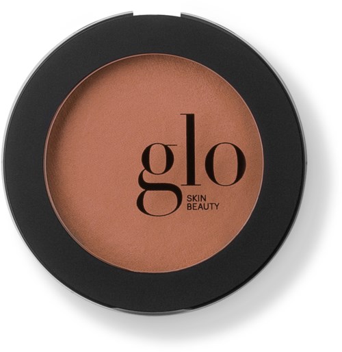 En rund kompakt med brunt pressat puder och svart yttre kant, märkt 'glo SKIN BEAUTY'.
