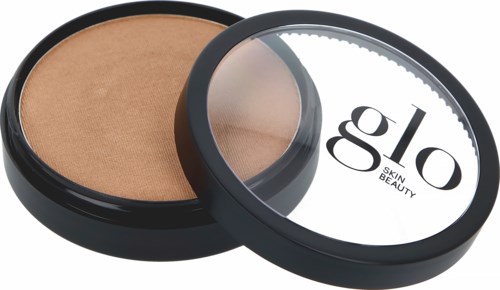 Ett rougepuder i en rund svart behållare med klart lock, märkt "glo SKIN & BEAUTY."