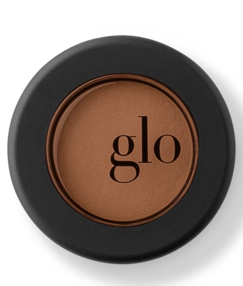 Ett runt sminkrougepuderbehållare med svart och brunt färg, och ordet "glo" på.