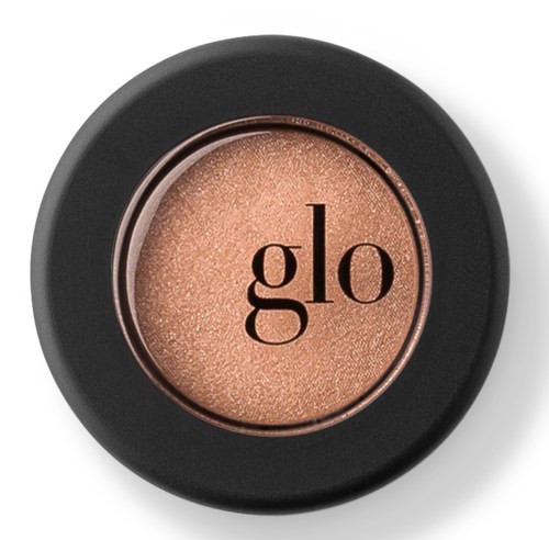 Ett runt skönhetsprodukt med svart skal och glänsande beige puder inuti, med ordet 'glo' på.