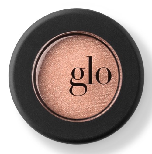 Ett runt skönhetsprodukt med svart vikning och en glänsande, persikofärgad mittdel märkt "glo".
