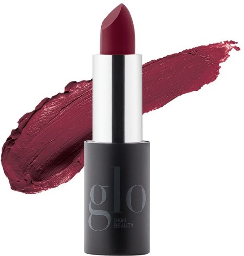 A dark lipstick in a silver and black tube with a large smear of deep red color next to it.