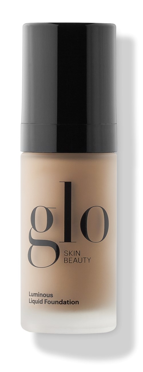 En flaske med Glo Skin Beauty lysende flytende foundation med svart lokk og beige væske inni.