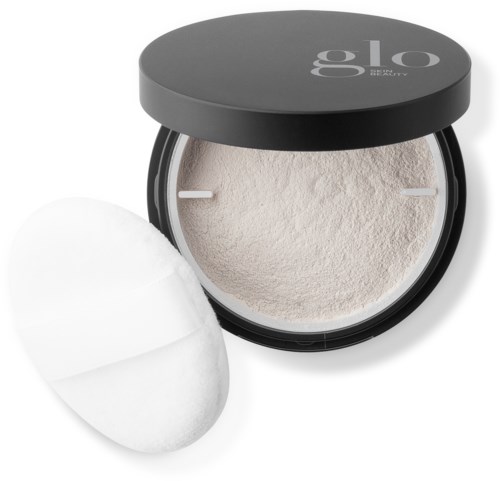 En svart rund beholder med hvitt pulver og en makeup-svamp inni.