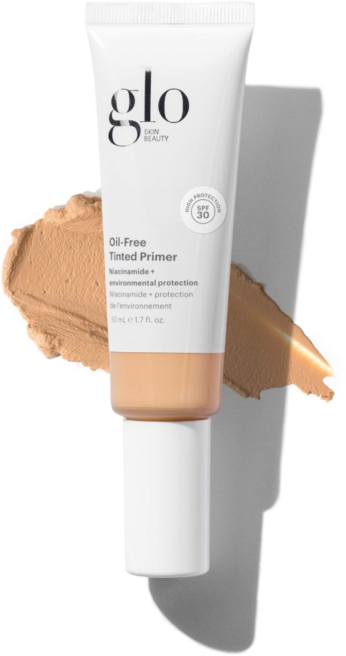 Valkoinen putki Glo skin beauty -primeria SPF 30 ja beige meikin taustalla. Varjo oikealla puolella.