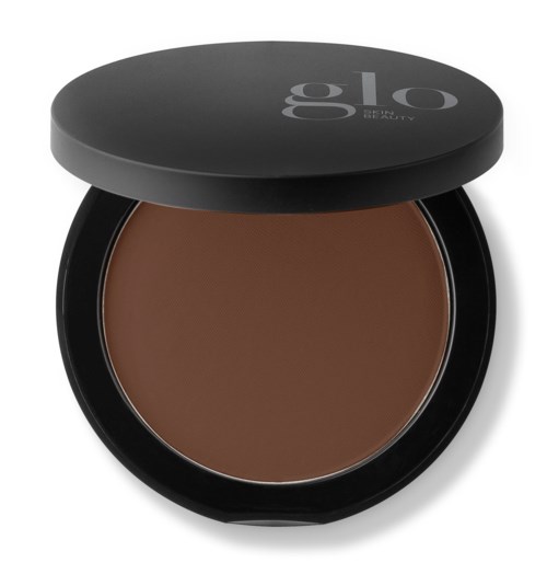 En rund åpen compact med brunt pulver og lokk som sier 'glo'.