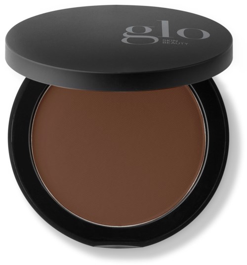 En liten beholder med en brun makeup innvendig, svart lokk med grå tekst som sier "glo BEAUTY."