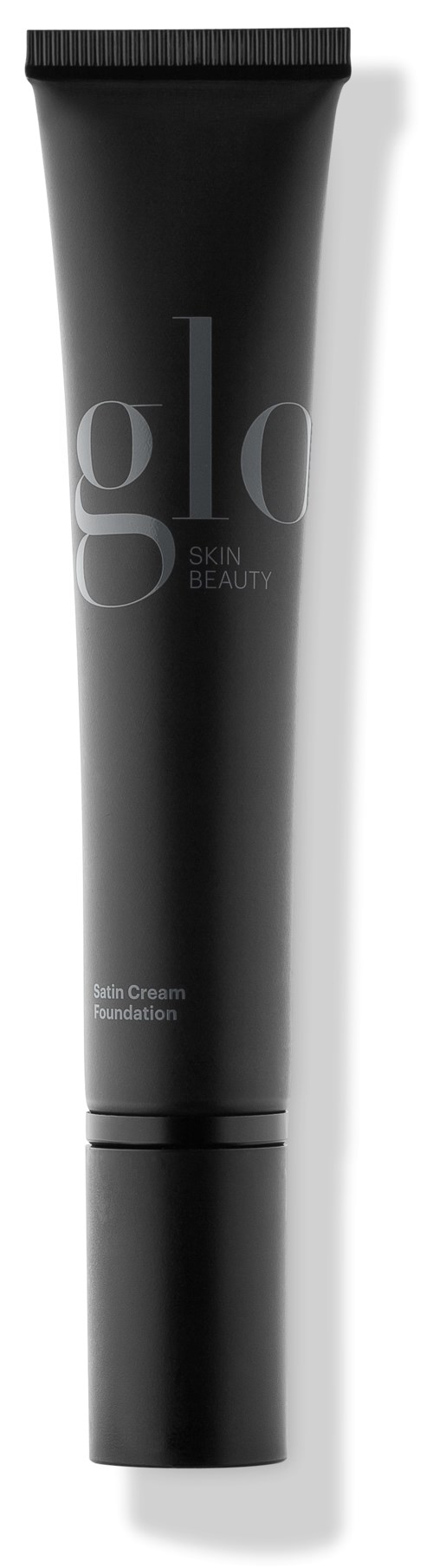 En svart tube med lokk og merket 'gold' og 'Skin, Beauty,' sannsynligvis et hudpleie- eller foundationprodukt.