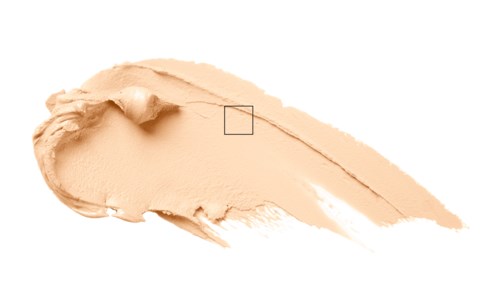 En beige sminke- eller kosmetikkrem med en liten kube og en tynn linje. Svart bakgrunn.