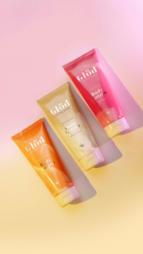 Three colorful body lotion tubes in pink, yellow, and orange are placed on a pastel background.