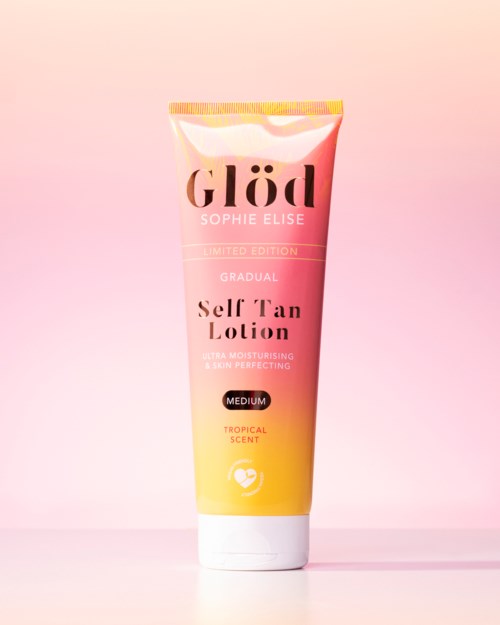 En tube med self-tan lotion med rosa til gul gradient, merket 'Glöd,' med duft og fuktighetsgivende egenskaper.